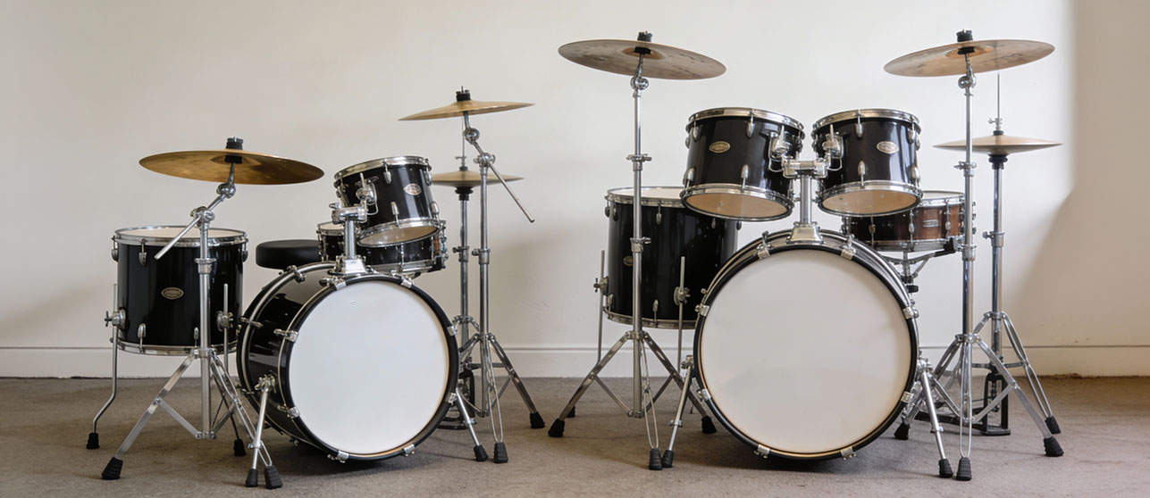 Side-by-side comparison showing a child-sized junior drum set next to a full-size adult drum kit demonstrating size differences