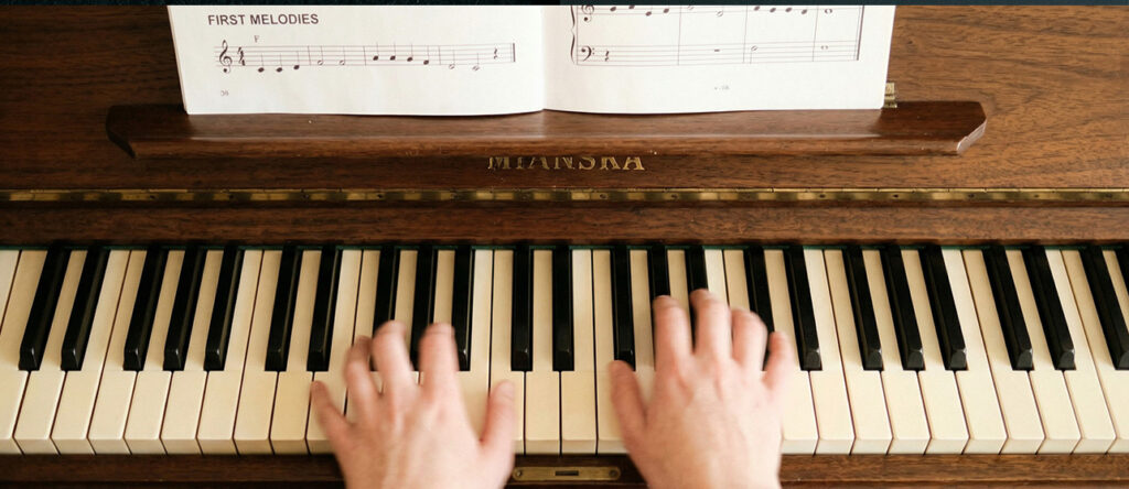 Beginner placing hands on piano keys during a first piano lesson