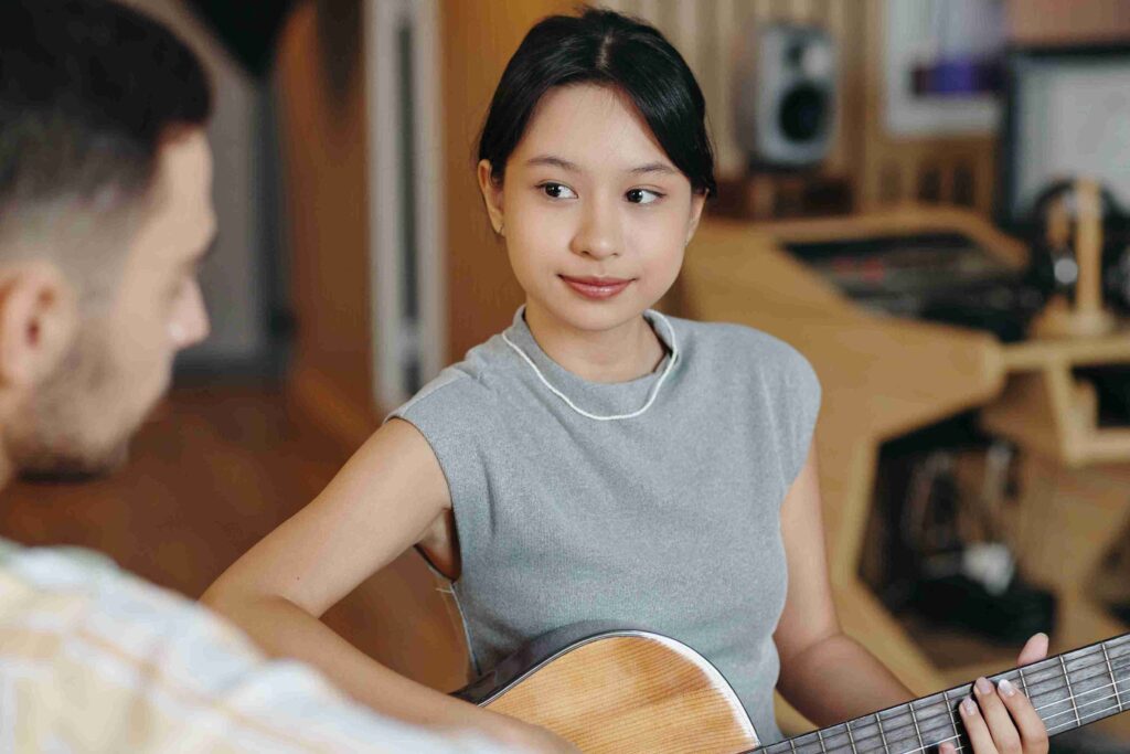 Student learning guitar during a music lesson in Singapore with guidance from a professional music instructor.