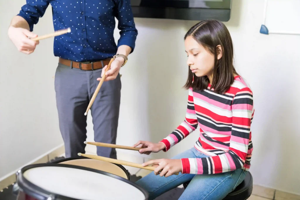 Student learning to play the drums with guidance from a music instructor during a beginner drum lesson in Singapore, building confidence and fundamental drumming skills.