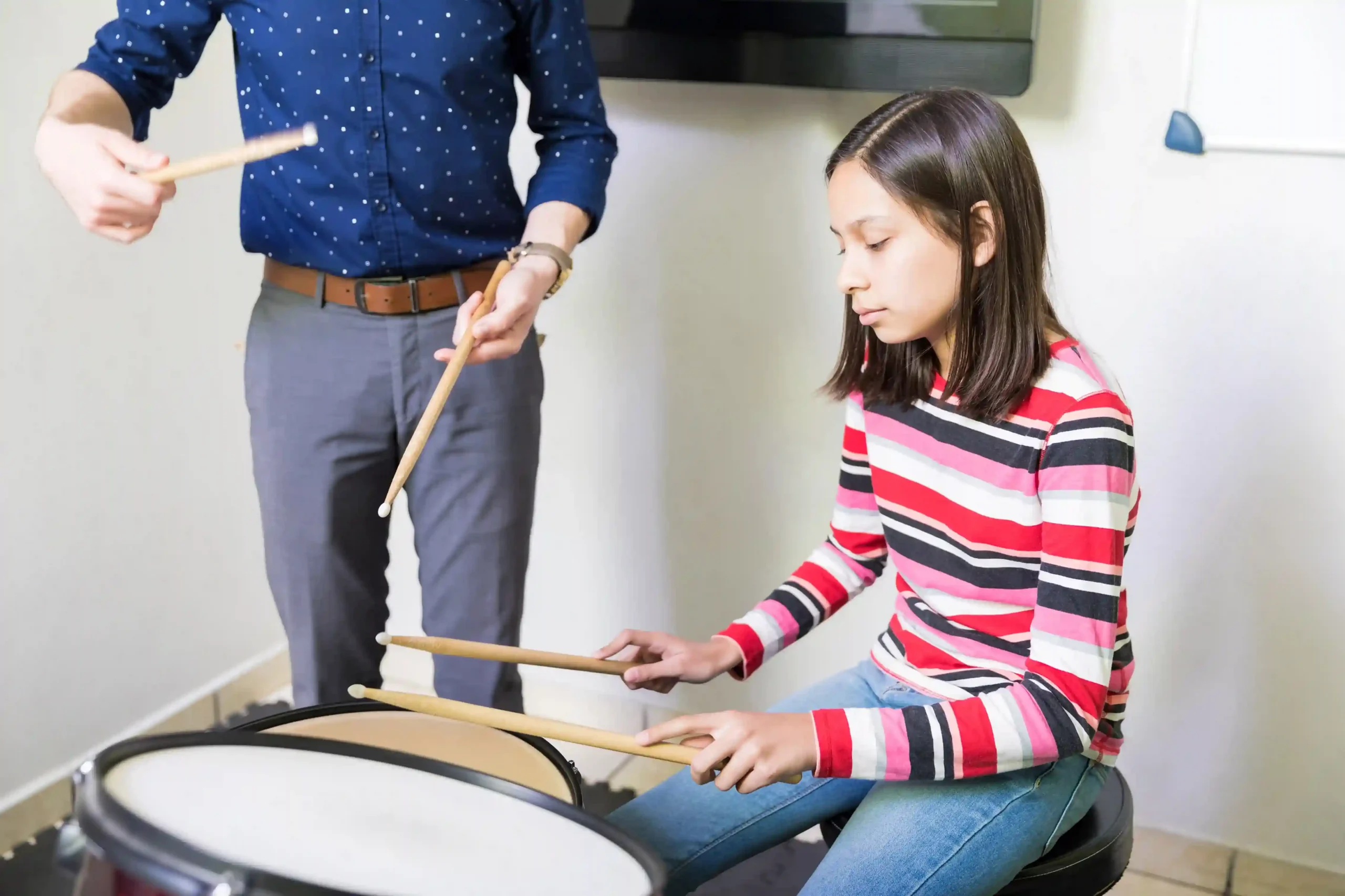 Student learning to play the drums with guidance from a music instructor during a beginner drum lesson in Singapore, building confidence and fundamental drumming skills.