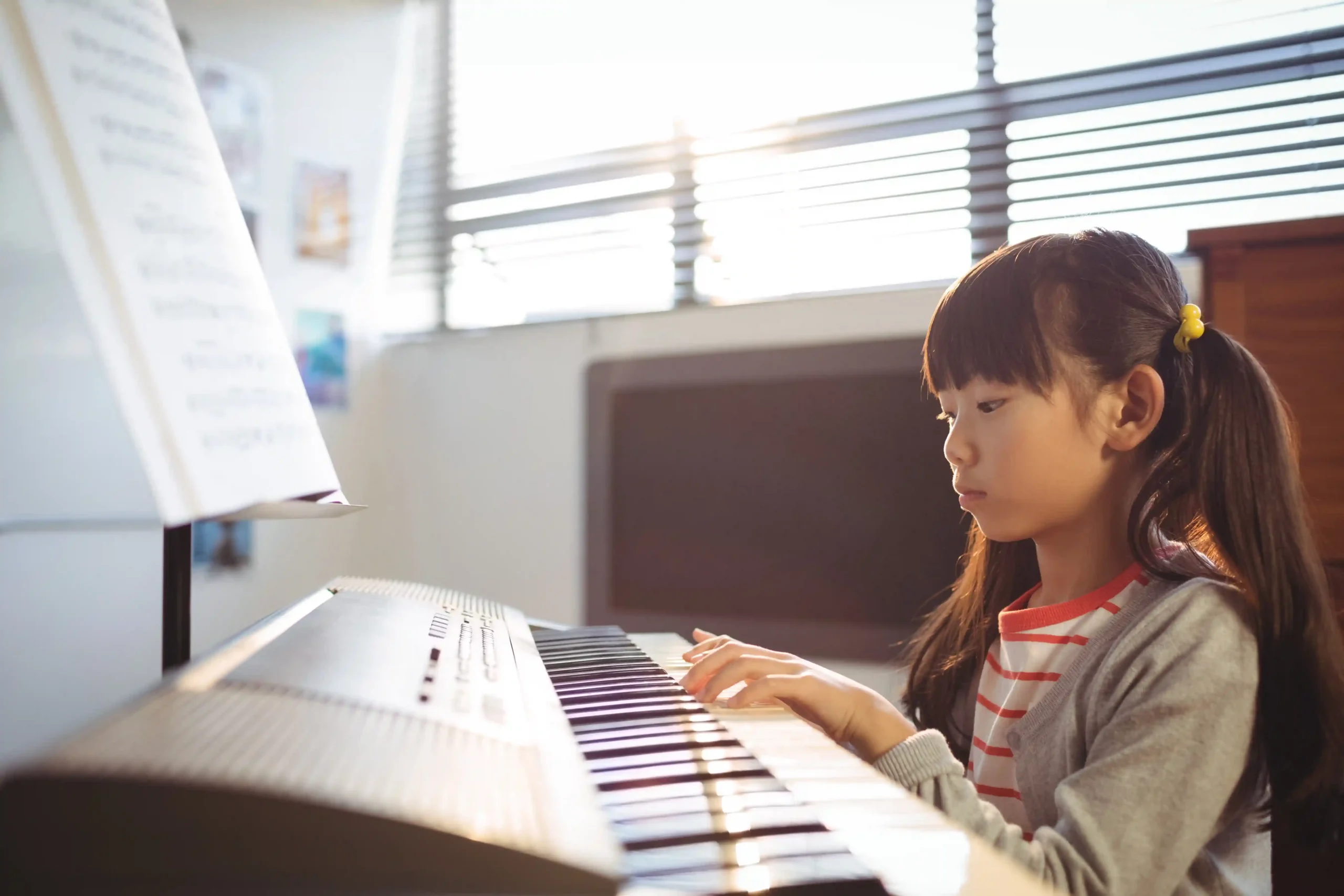 Young girl practising piano, illustrating what age should kids start piano lessons.